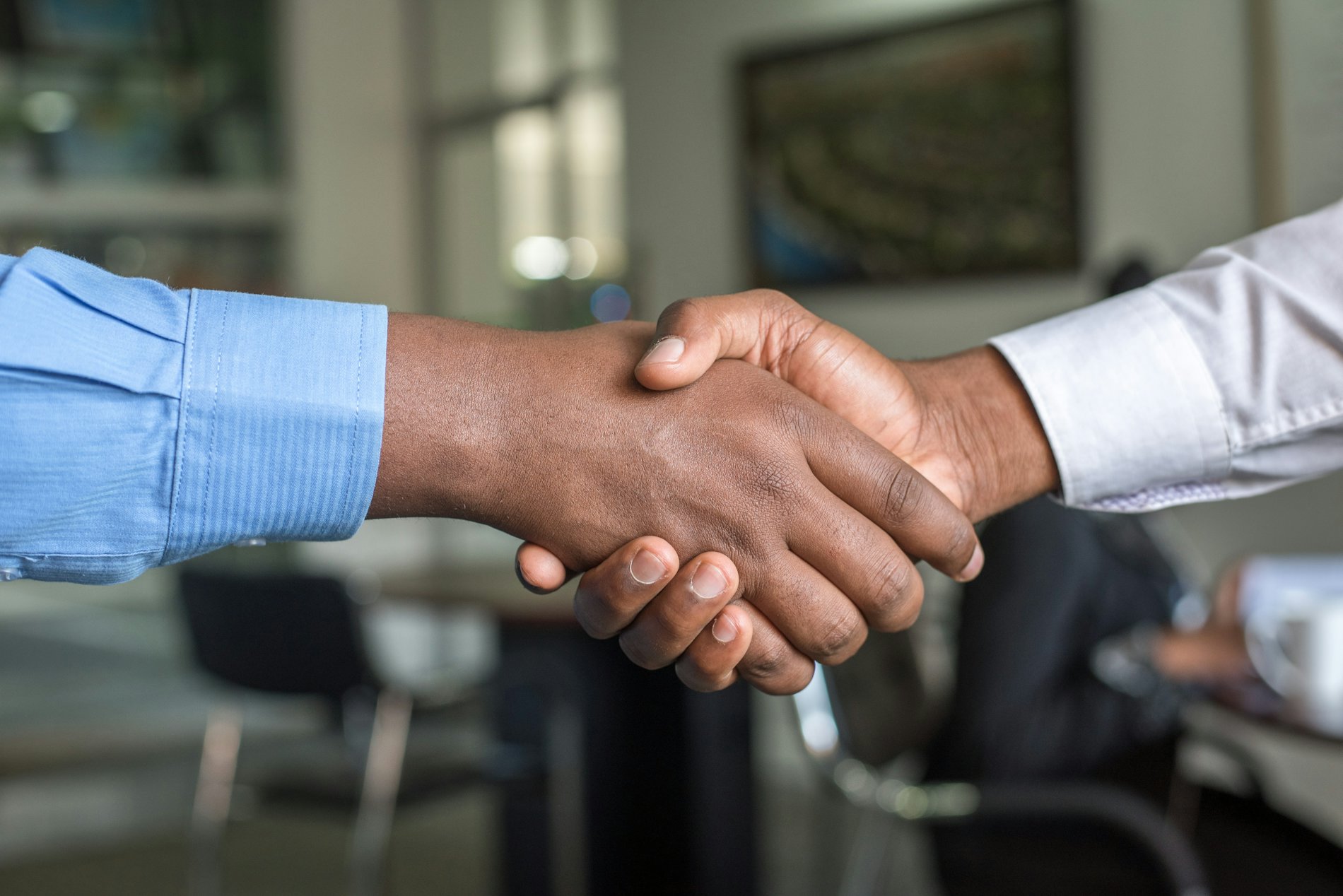 Two professionals shaking hands in an office, representing a trusted business partnership.